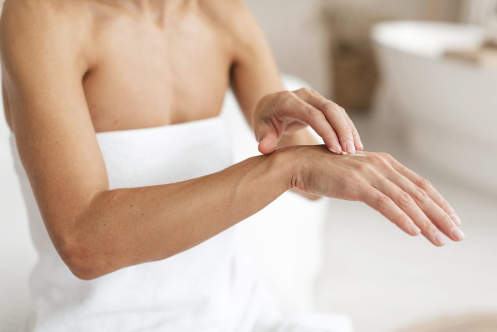 A woman in a bath towel with a hand touching her skin, showing how hard water can impact cleanliness and the feeling on skin.